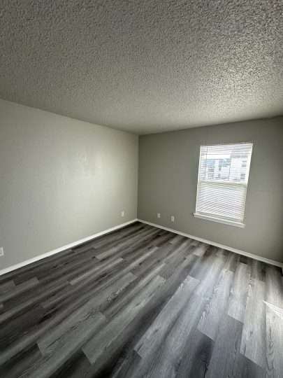 empty room with hardwood floors and gray walls at The Creekside Apartment Homes