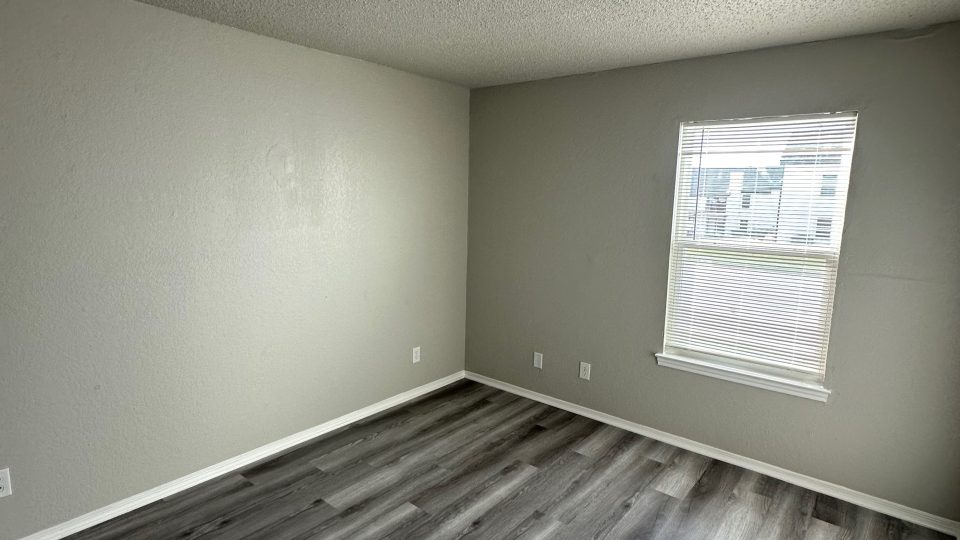 empty room with hardwood floors and gray walls at The Creekside Apartment Homes