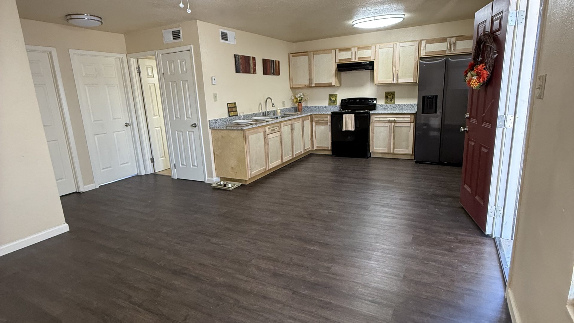 a large empty room with hardwood floors and ceiling fans at The Delmar Place Apartment
