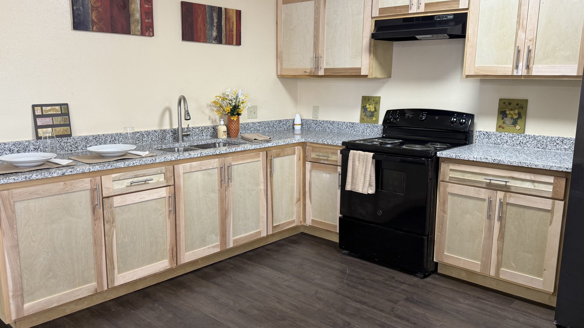 a kitchen with black appliances and wood cabinets at The Delmar Place Apartment