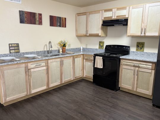 a kitchen with black appliances and wood cabinets at The Delmar Place Apartment