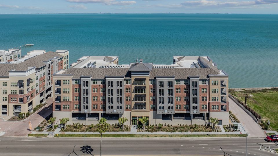 an aerial view of a condo building with the ocean in the background at The Alexa