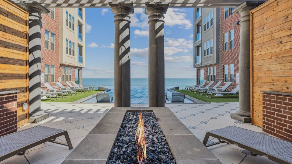 the patio has a fire pit and lounge chairs at The Alexa