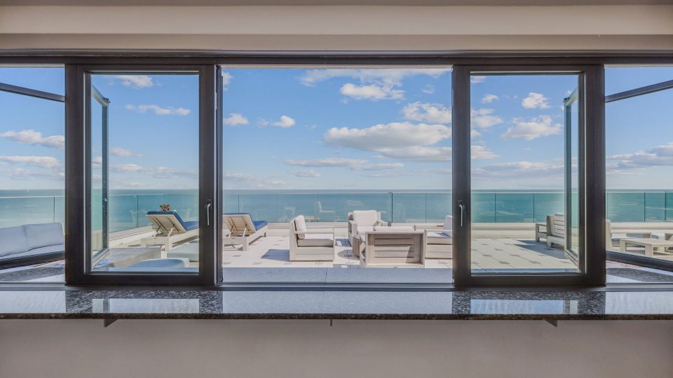 a large window overlooking the ocean and the beach at The Alexa
