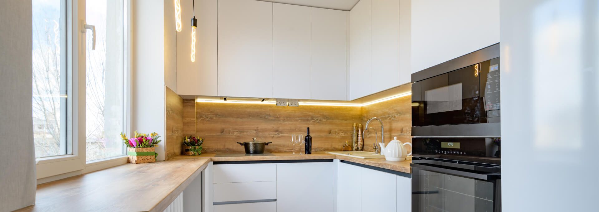 a kitchen with white cabinets and wooden floors at The  Apiary