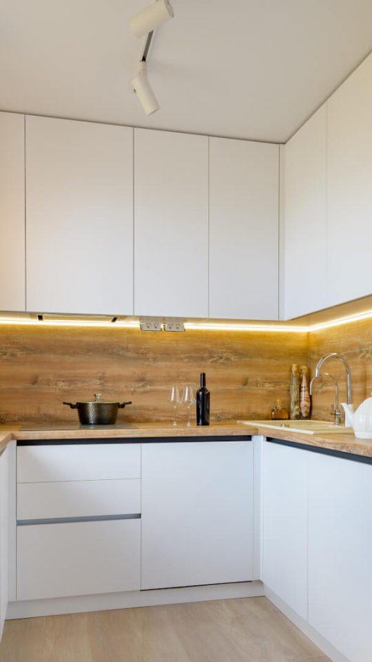 a kitchen with white cabinets and wooden floors at The  Apiary