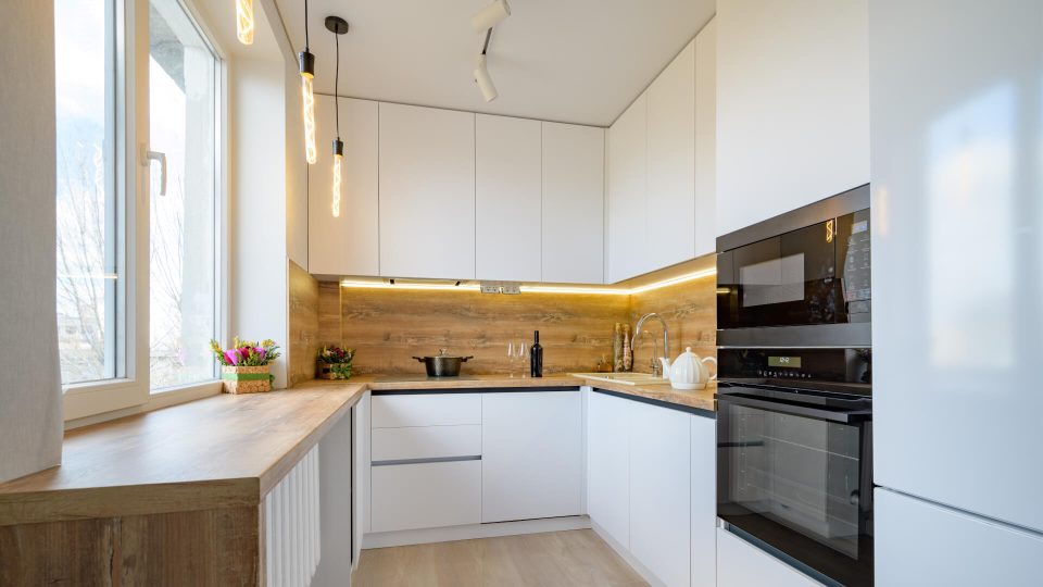 a kitchen with white cabinets and wooden floors at The  Apiary