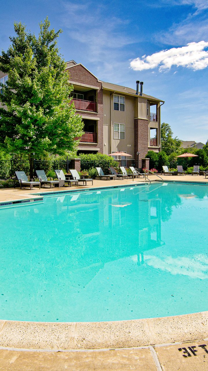 Outdoor swimming pool and sundeck surrounded by trees and apartment buildings at Ovaltine Court in Villa Park, Illinois