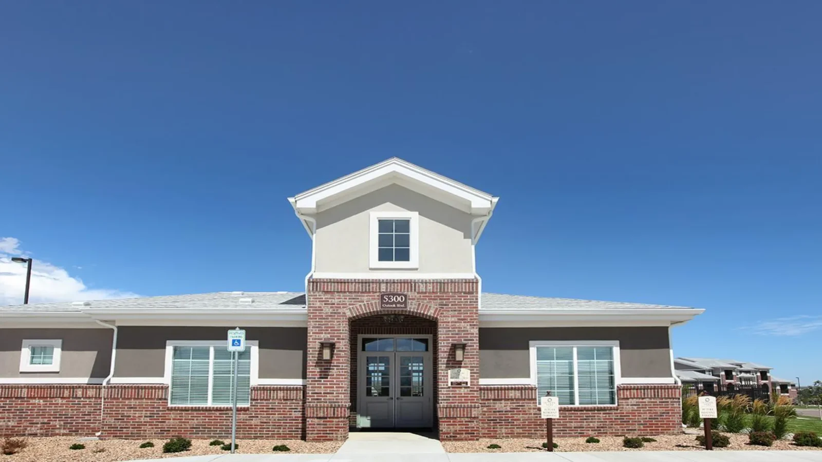 the front of a building with a driveway and a sign that says welcome at The Outlook Ridge Apartments