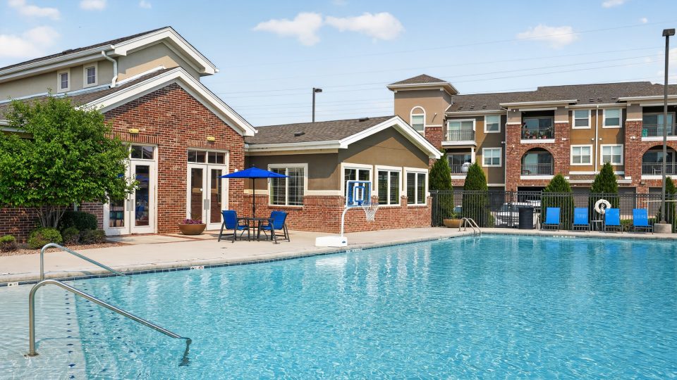 Outlook Ridge Apartments Exterior: Large, sparkling pool with clubhouse, ample seating, and a modern apartment building nearby.