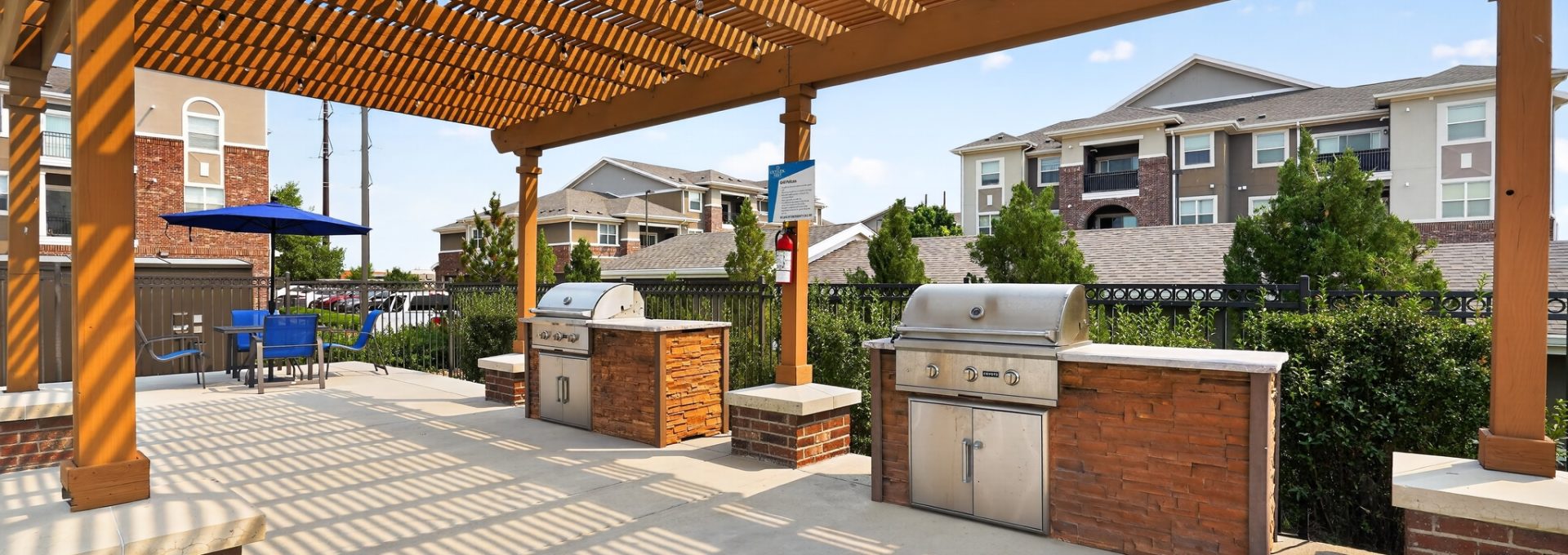 Outlook Ridge Apartments Exterior: Apartment community's outdoor amenity with two built-in grills, shaded pergola, patio seating.