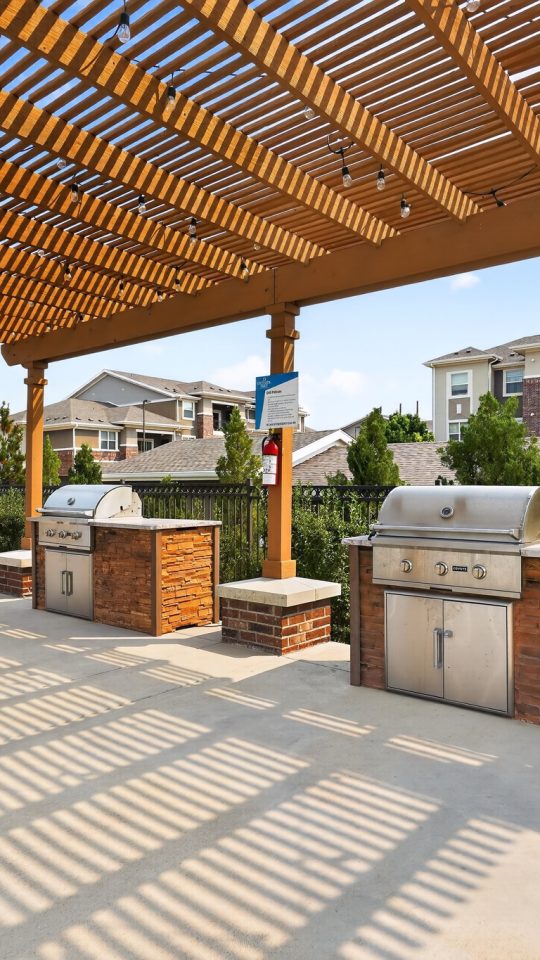 Outlook Ridge Apartments Exterior: Apartment community's outdoor amenity with two built-in grills, shaded pergola, patio seating.