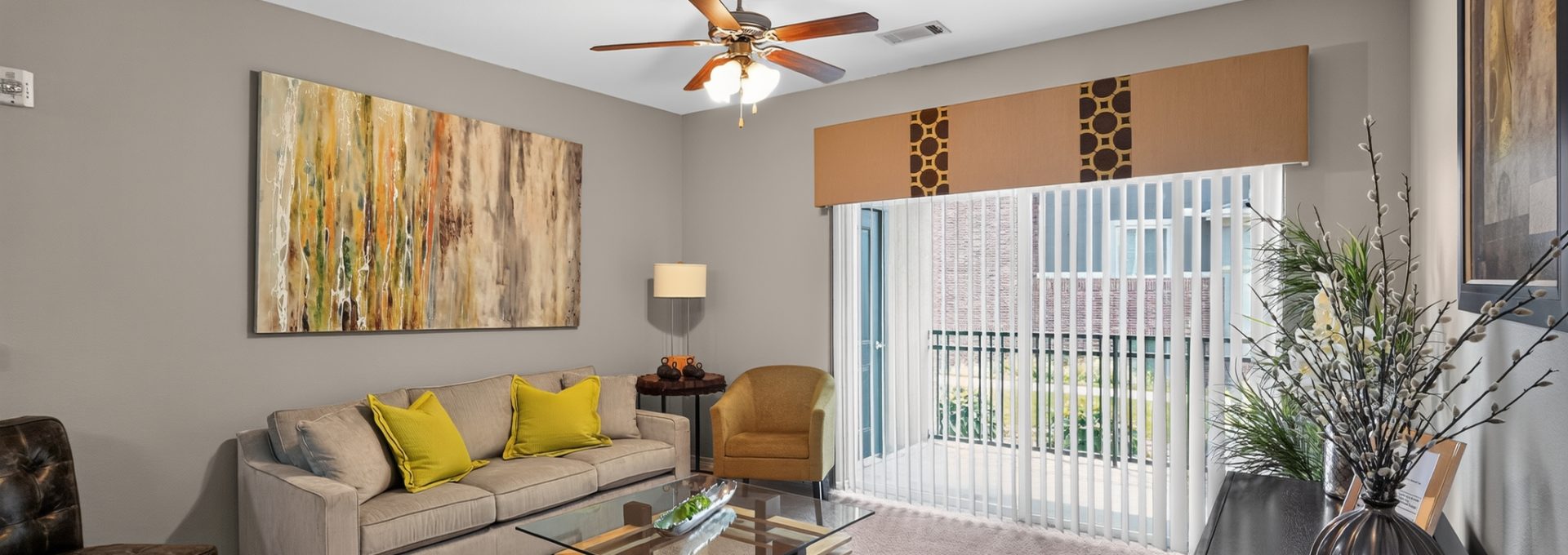 Outlook Ridge Apartments apartment living room: Modern, furnished space with light carpet, a tan couch, and a large balcony door.
