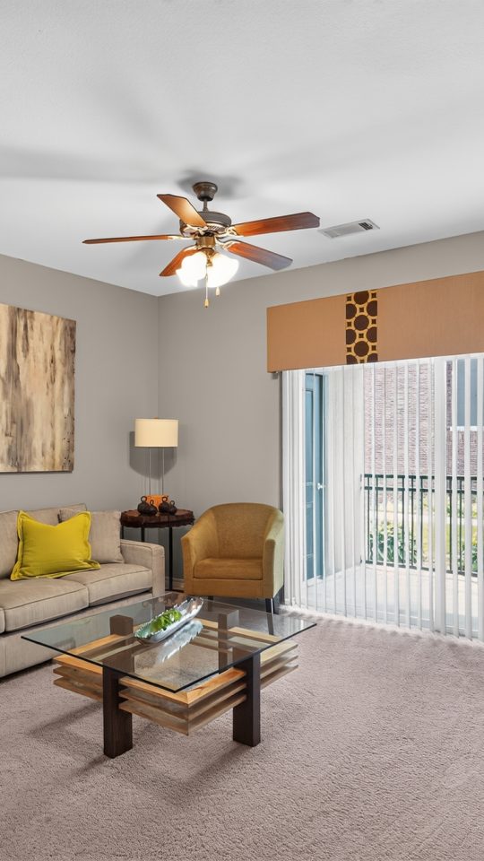 Outlook Ridge Apartments apartment living room: Modern, furnished space with light carpet, a tan couch, and a large balcony door.