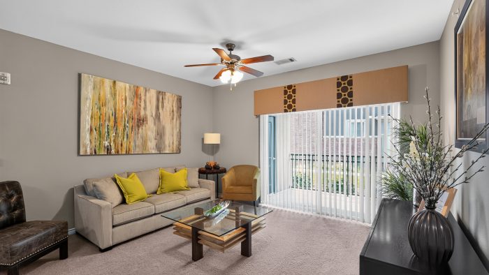 Outlook Ridge Apartments apartment living room: Modern, furnished space with light carpet, a tan couch, and a large balcony door.