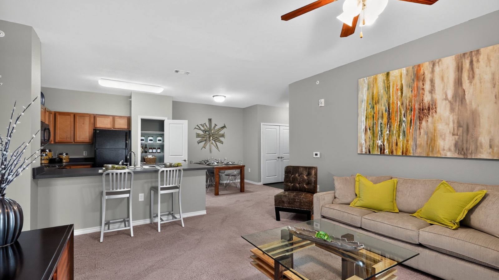 Open concept living room, dining, and kitchen with wood cabinets, black appliances, and a ceiling fan.