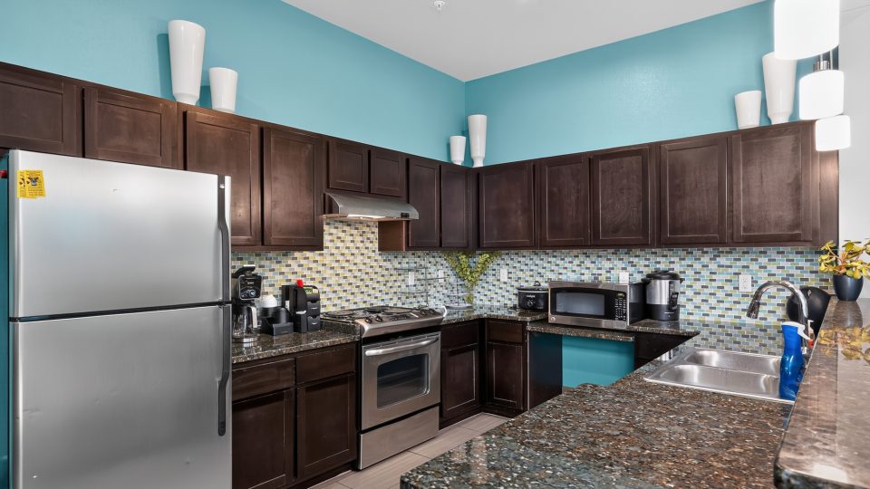 Outlook Ridge Apartments Kitchen: bright blue walls, dark cabinets, stainless steel appliances, granite counters, colorful tile.