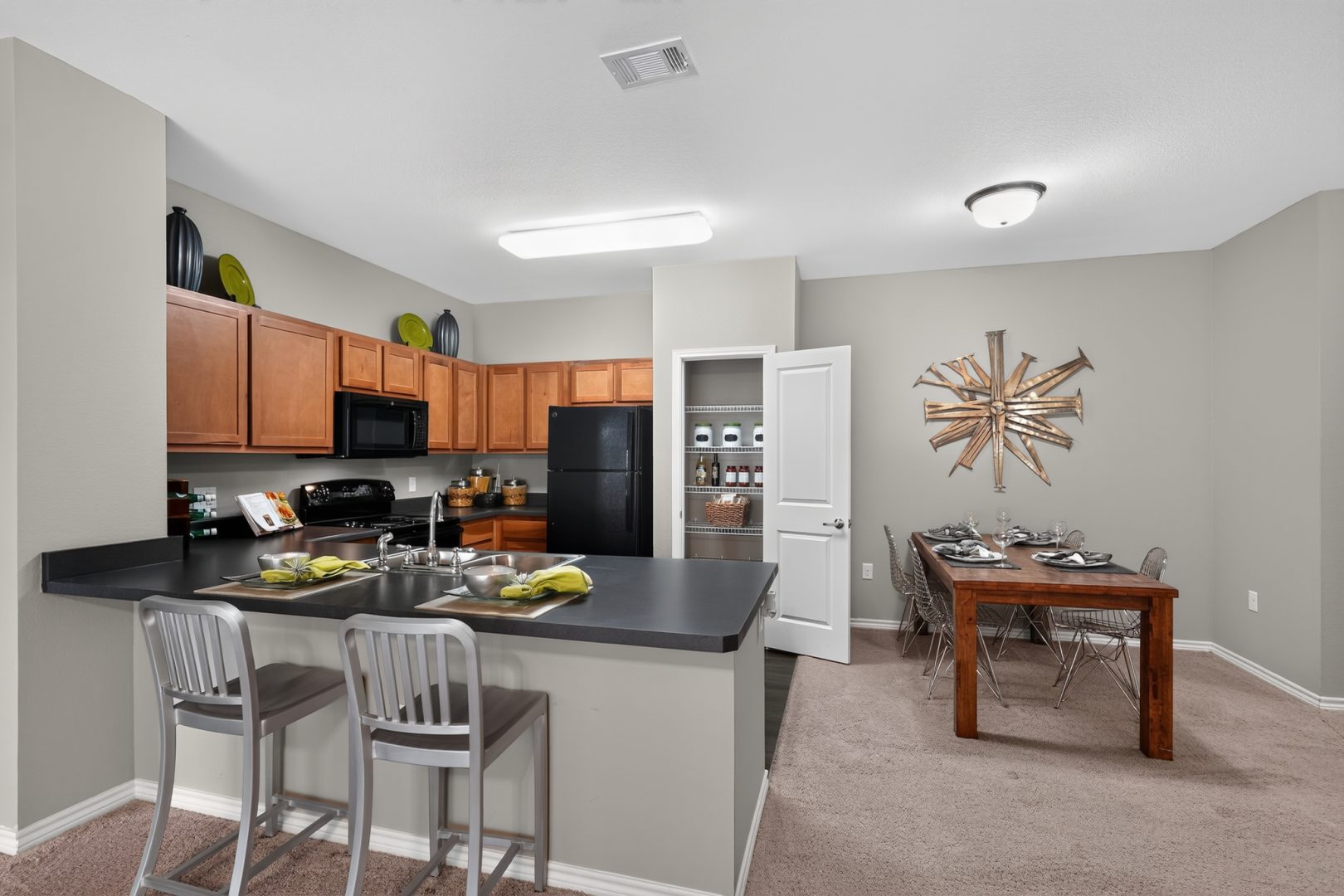 Open concept kitchen featuring wood cabinets, black appliances, and bar seating. Dining room with a wood table.