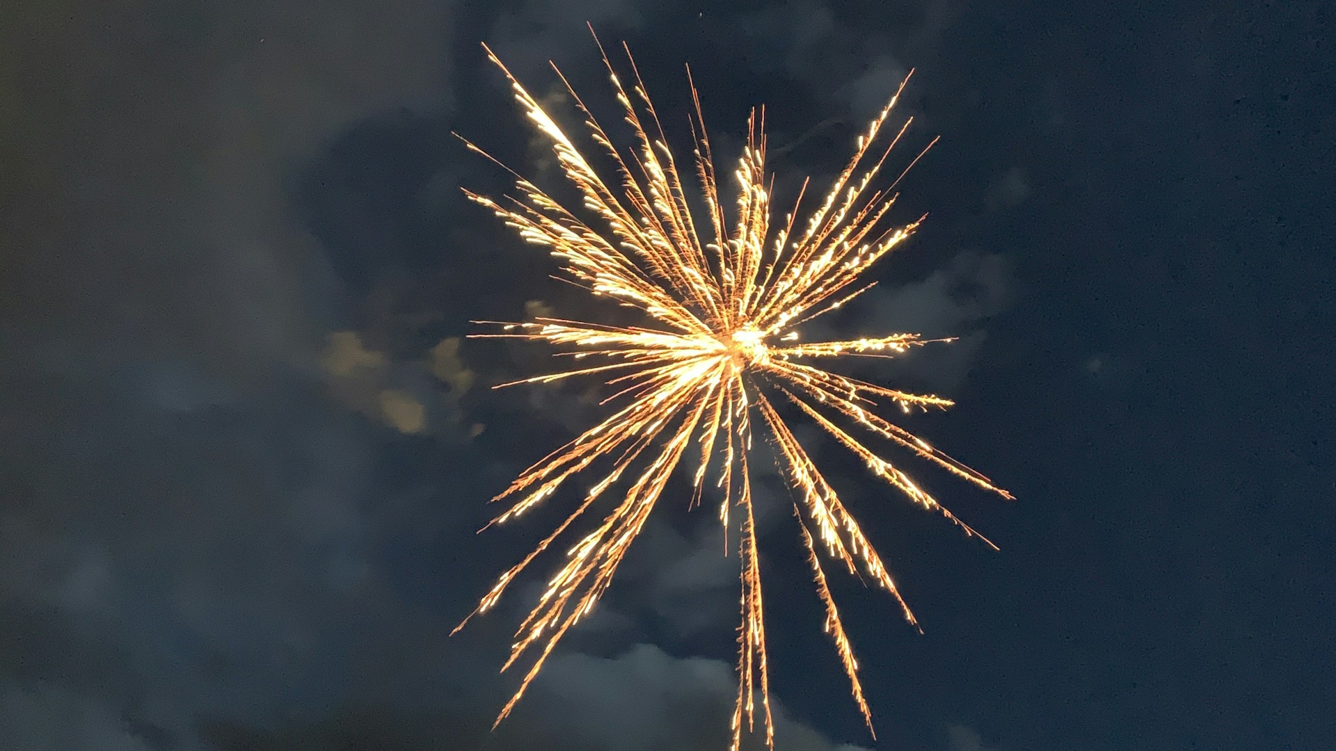 Yellow fireworks bursting in a cloudy night sky -- The Monarch at Mueller, Austin TX