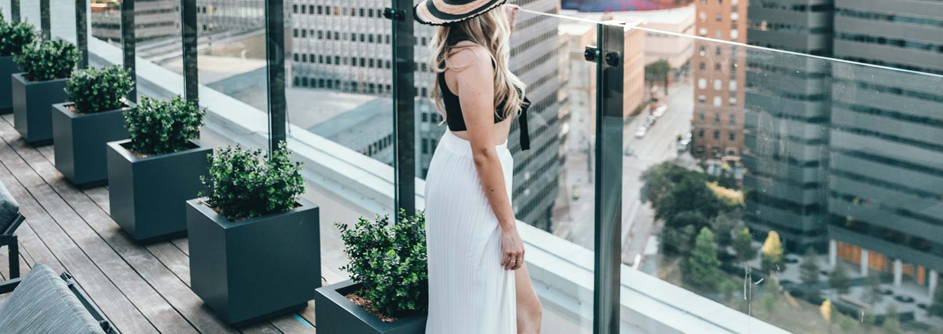 a woman in a white dress and hat is standing on a balcony at The  First