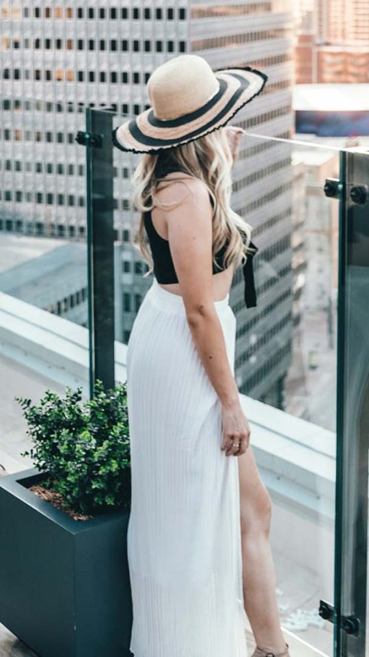 a woman in a white dress and hat is standing on a balcony at The  First