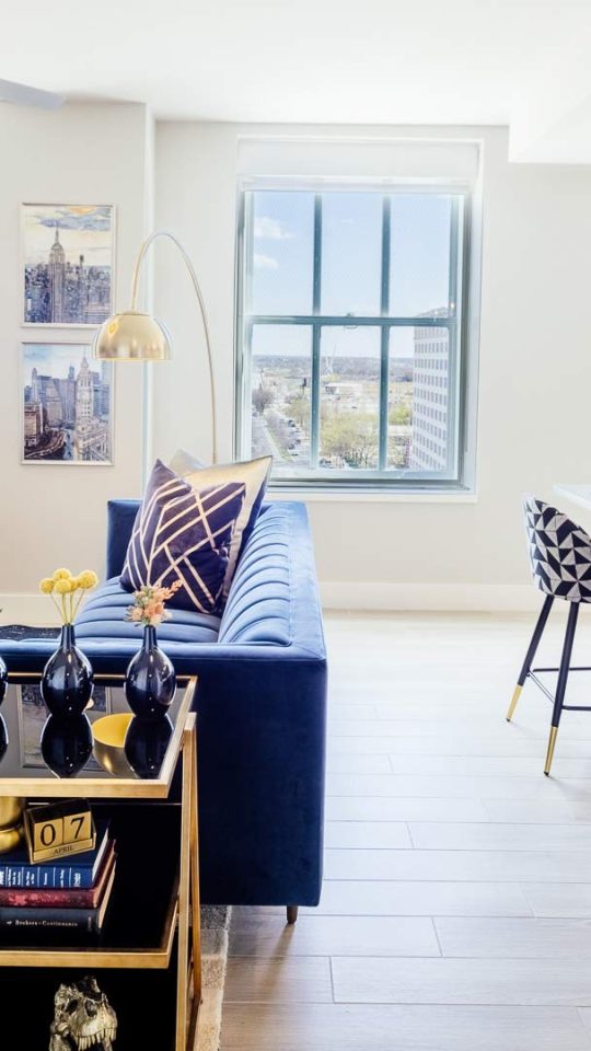 a living room with a blue couch and a white table at The  First