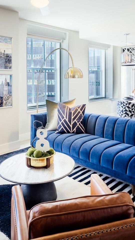 a living room with blue furniture and a large window at The  First