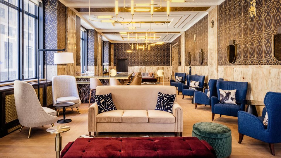 the lobby of a hotel with blue chairs and couches at The First