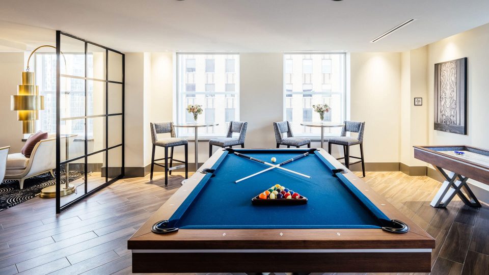 a pool table in a living room with chairs at The First