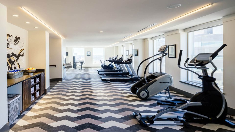 a gym with tread machines and a chevron patterned floor at The First