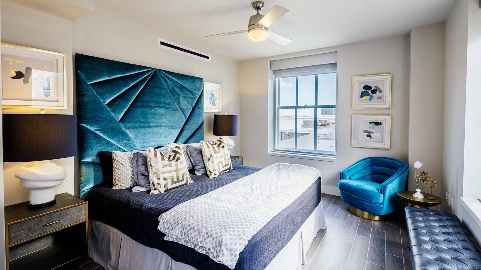 a bedroom with a blue headboard and a blue chair at The First