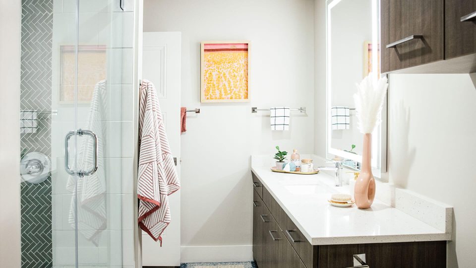 a bathroom with a shower and sink and a towel rack at The First