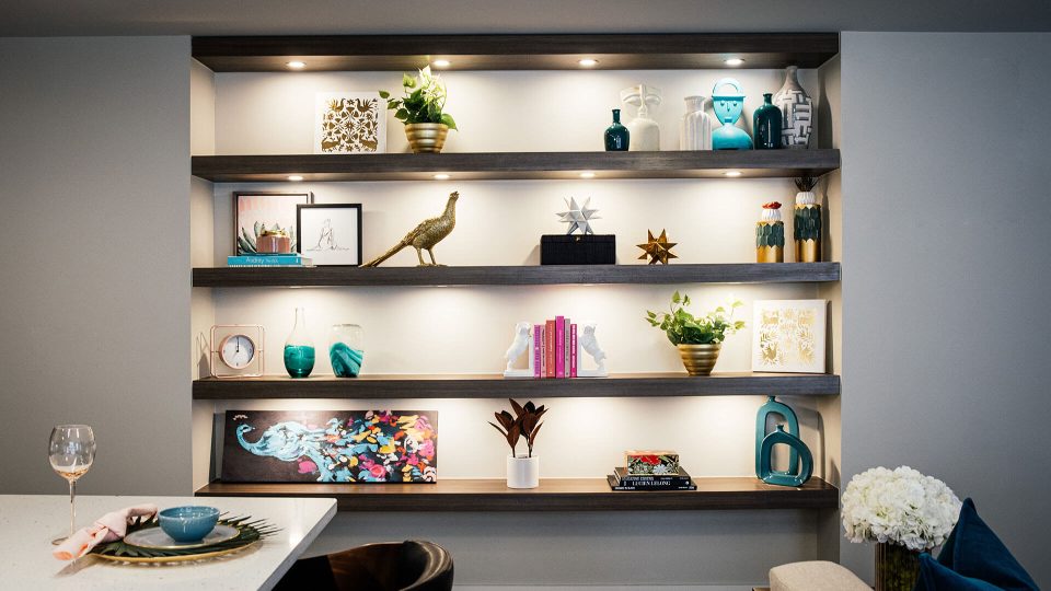 a modern dining room with shelves and a vase at The First