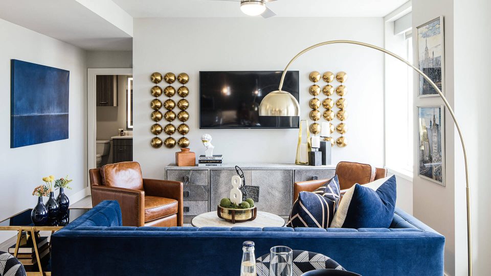 a living room with blue couches and a large flat screen tv at The First