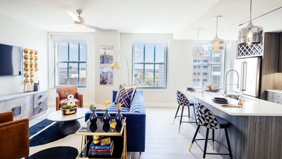 a living room with a blue couch and a large window at The First