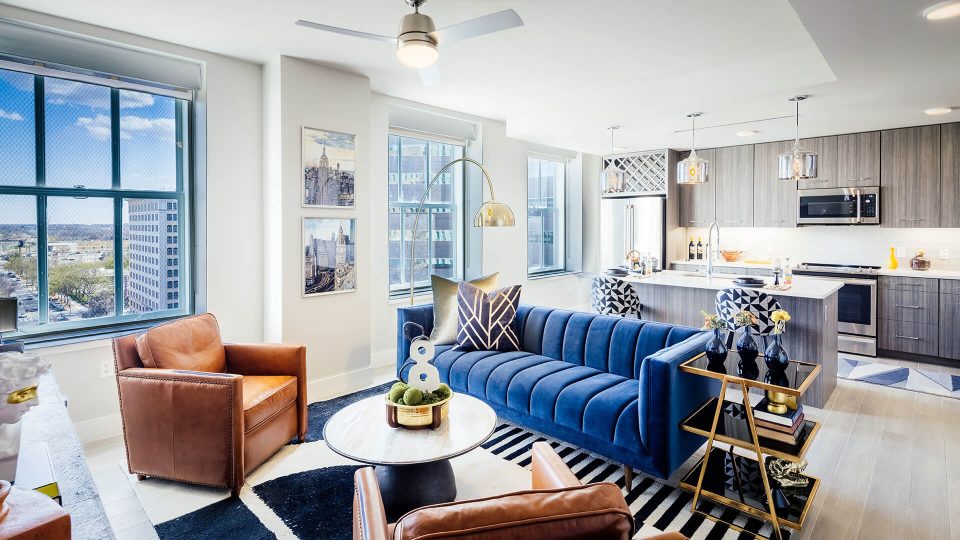 a living room with blue furniture and a large window at The First