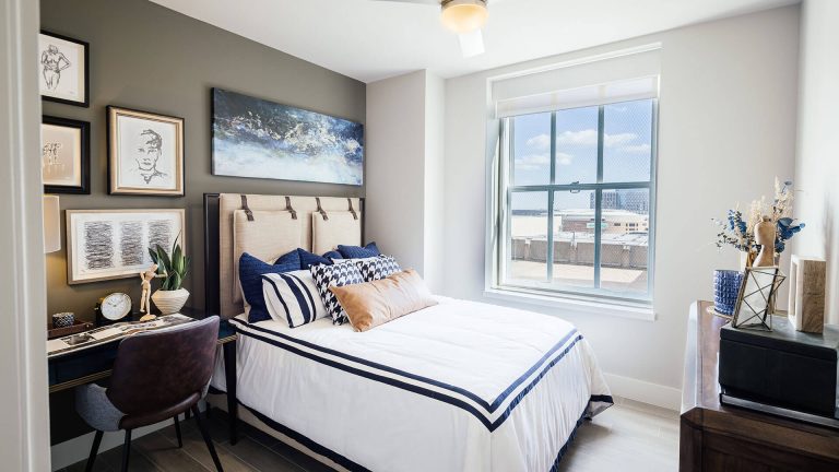 a bedroom with a bed, desk, and pictures on the wall at The  First