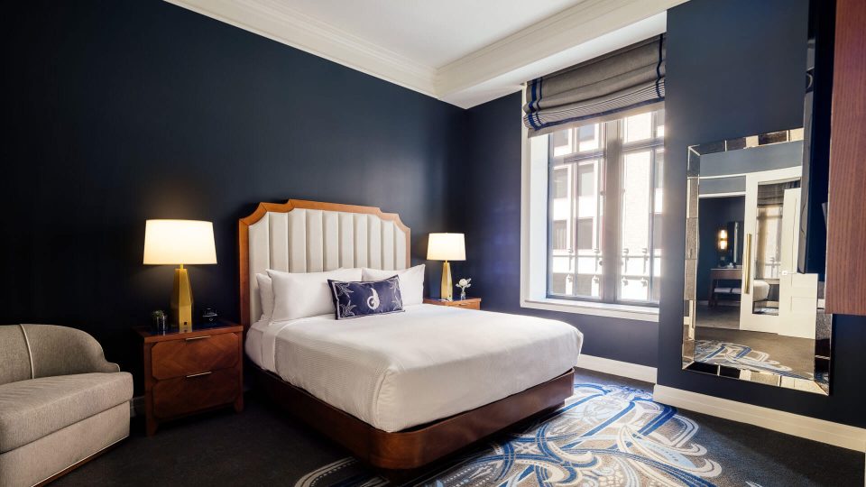 a hotel room with blue walls and a large bed at The First