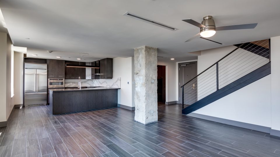 an empty living room with hardwood floors and a staircase at The First