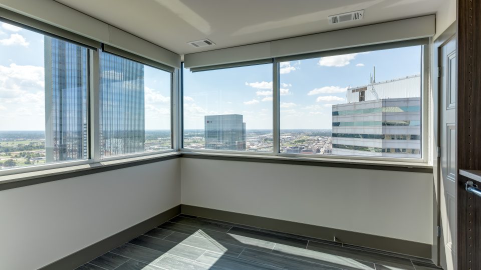 an empty room with large windows and a view of the city at The First