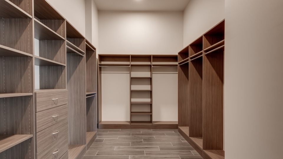 a walk in closet with shelves and cabinets at The First