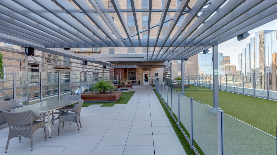 a rooftop patio with a pergolized roof and artificial turf at The First