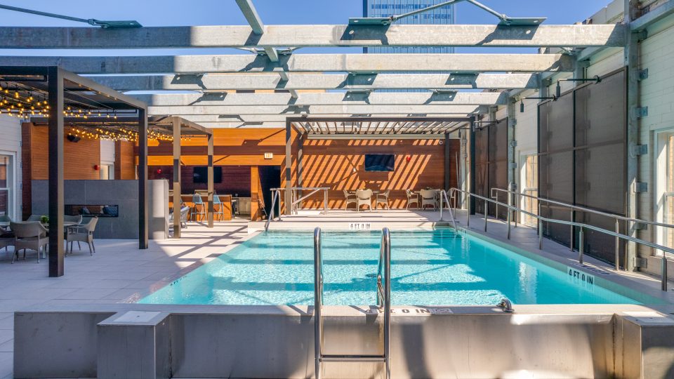 a pool with a sun roof and a patio at The First
