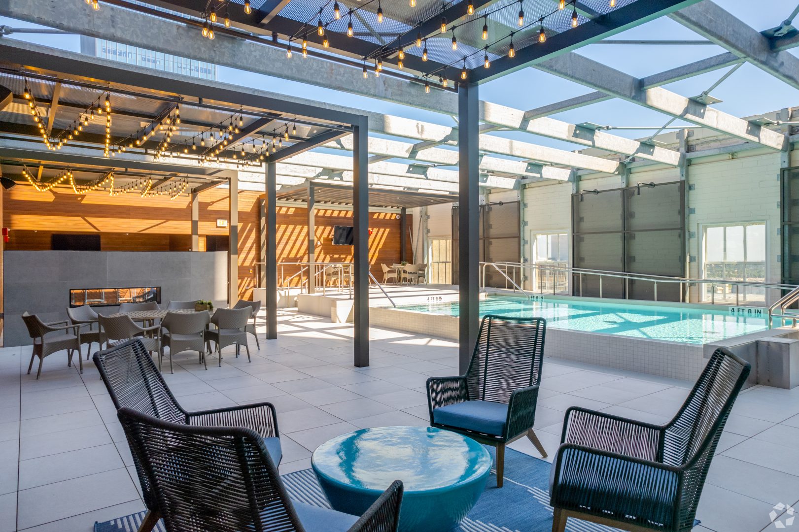 the patio area with chairs and tables near a pool at The  First