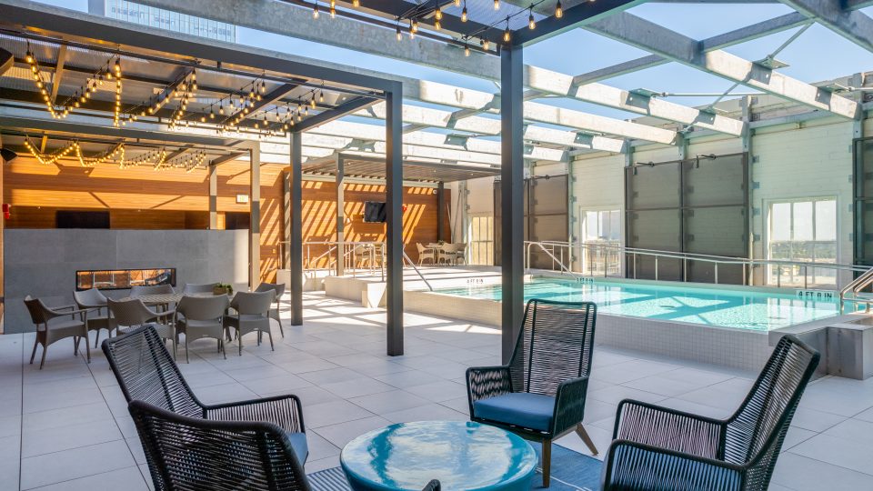 the patio area with chairs and tables near a pool at The First