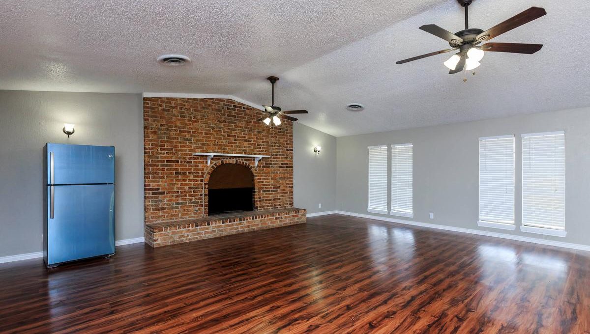 Spacious apartment living room with hardwood floors and brick fireplace at 1000 Mary Apartment Homes