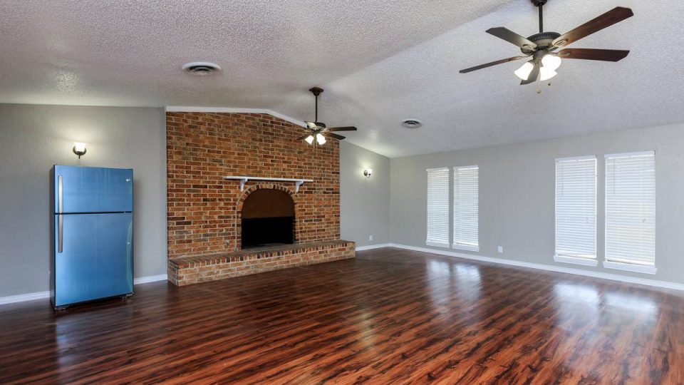 Spacious apartment living room with hardwood floors and brick fireplace at 1000 Mary Apartment Homes