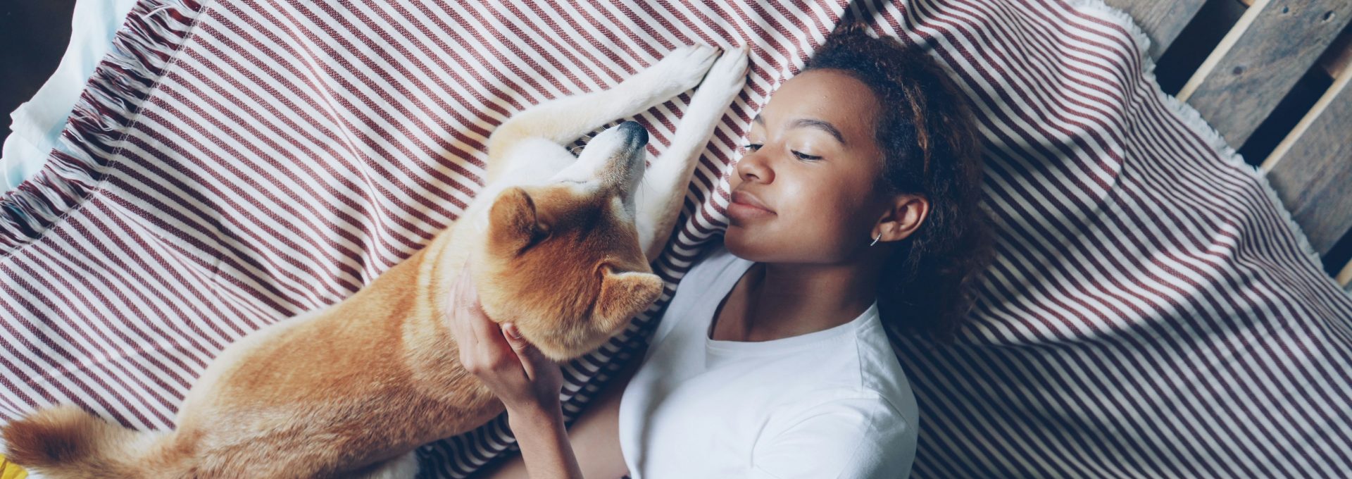 A woman lays with her dog on a bed.