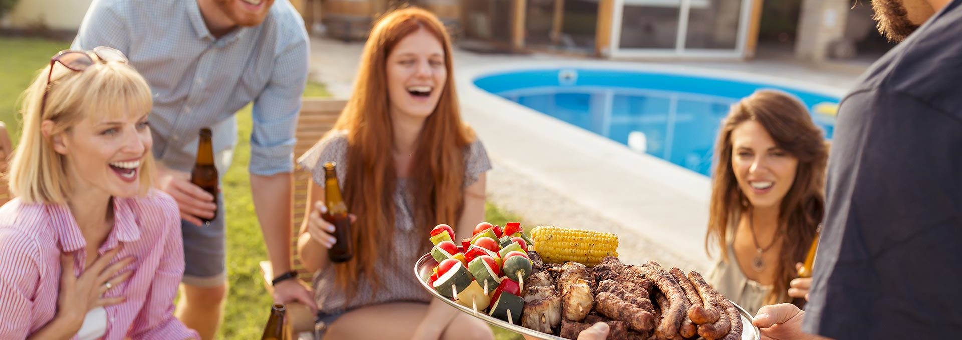 a group of people are having a barbecue at a pool at The Cedars Apartments