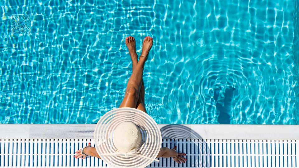 a woman in a hat and white dress is standing in a pool at The Cedars Apartments